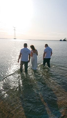 Dopeling en begeleiders lopen het water in